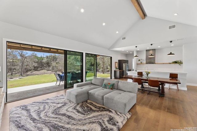 living room with high vaulted ceiling, beam ceiling, hardwood / wood-style flooring, and visible vents