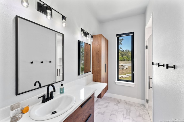 bathroom featuring marble finish floor, vanity, and baseboards