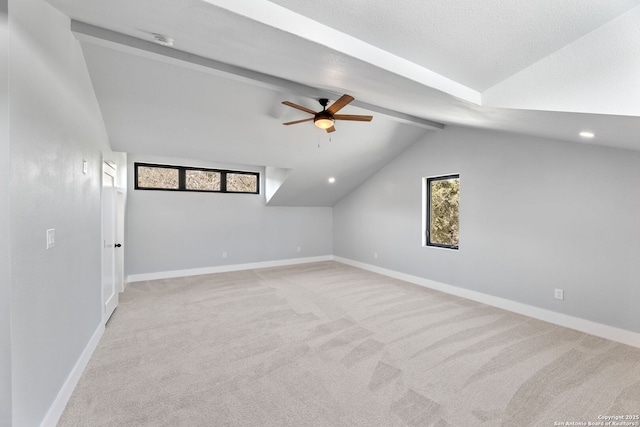 additional living space with a ceiling fan, light carpet, vaulted ceiling with beams, and baseboards