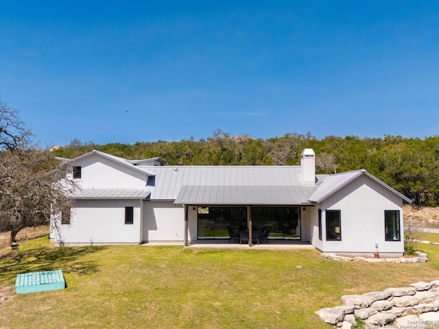 back of property with metal roof, a patio, a yard, a standing seam roof, and a chimney