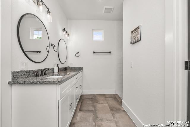 bathroom with a wealth of natural light, a sink, baseboards, and double vanity