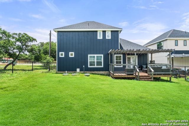 rear view of property featuring a pergola, a lawn, fence, a deck, and board and batten siding