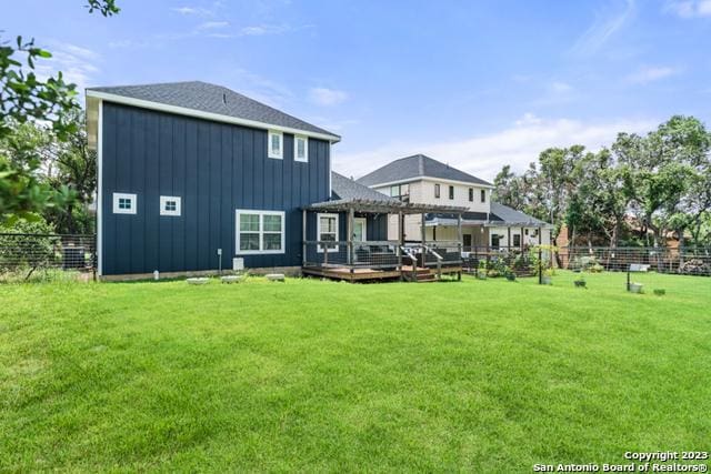 back of property featuring a lawn, board and batten siding, fence, a deck, and a pergola