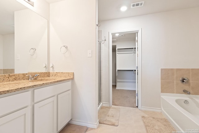 bathroom with a stall shower, visible vents, a spacious closet, vanity, and a bath