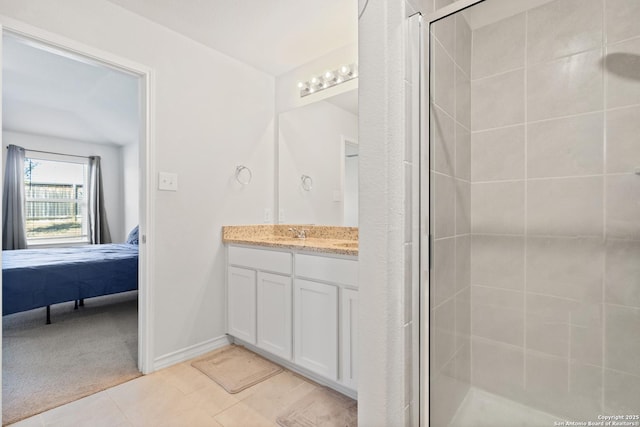 ensuite bathroom with ensuite bathroom, vanity, baseboards, tile patterned floors, and a stall shower