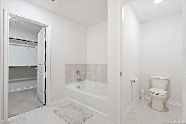 full bath with toilet, visible vents, baseboards, a bath, and a walk in closet