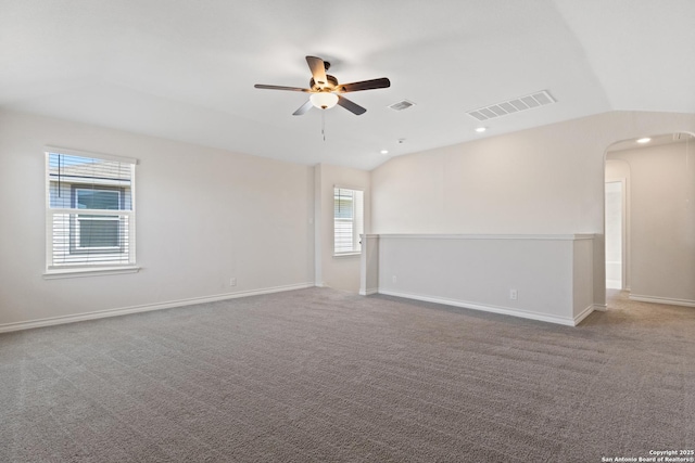 spare room featuring vaulted ceiling, arched walkways, visible vents, and a ceiling fan