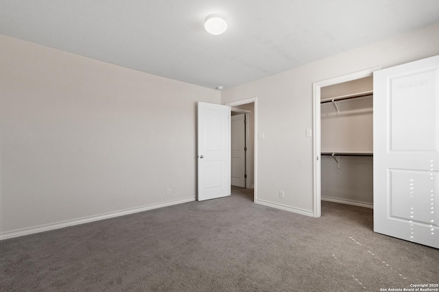 unfurnished bedroom with carpet floors, a spacious closet, baseboards, and a closet