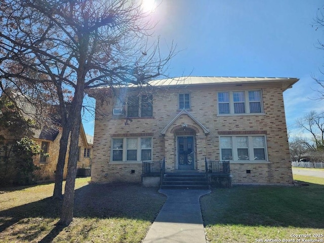 view of front of property with metal roof, a front lawn, and brick siding