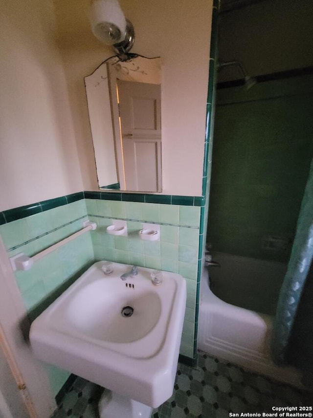 bathroom featuring wainscoting, a sink, tile walls, and tub / shower combination