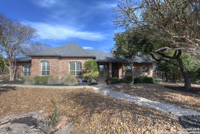 view of front facade with roof with shingles and brick siding