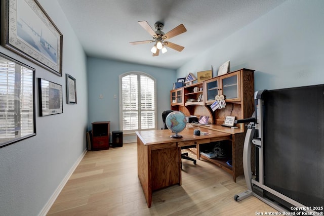 office area featuring a ceiling fan, light wood-type flooring, and baseboards