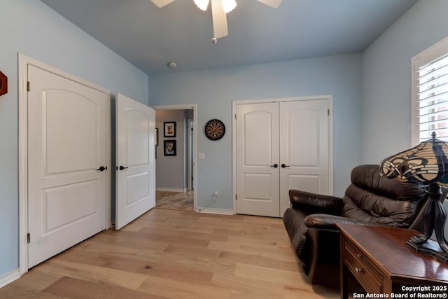 sitting room featuring baseboards, a ceiling fan, and light wood-style floors