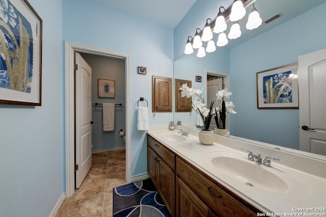 full bath featuring double vanity, a sink, visible vents, and baseboards