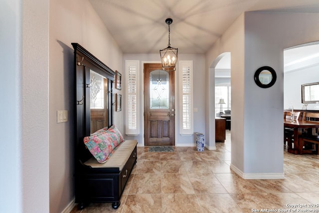 foyer entrance with baseboards, a wealth of natural light, and a notable chandelier