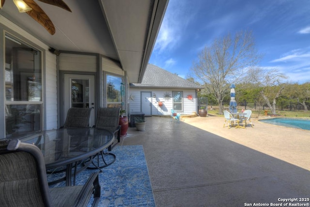 view of patio with outdoor dining space, fence, and a fenced in pool