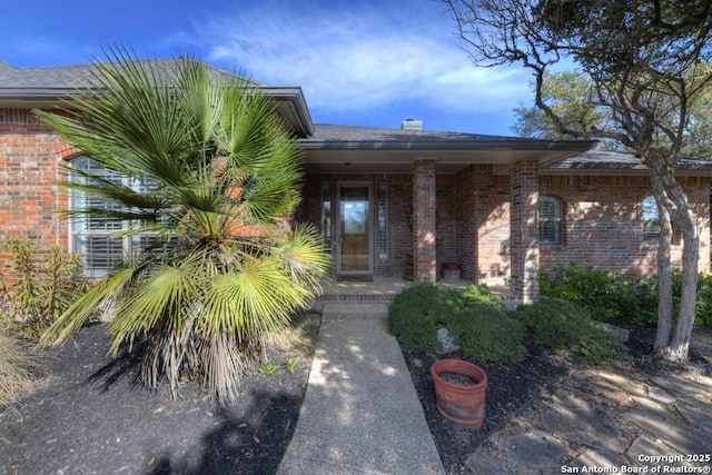 view of exterior entry featuring covered porch and brick siding