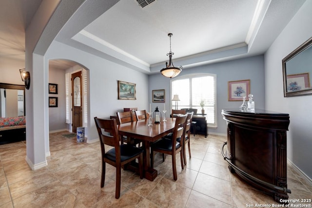 dining room featuring arched walkways, a raised ceiling, visible vents, light tile patterned flooring, and baseboards