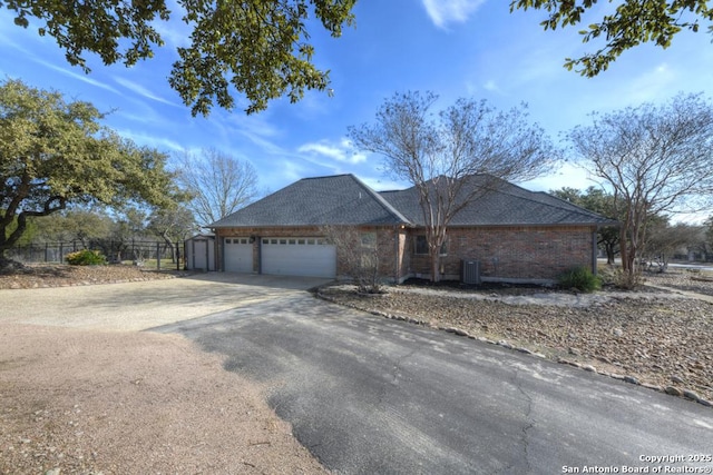 single story home with brick siding, an attached garage, central AC unit, fence, and driveway