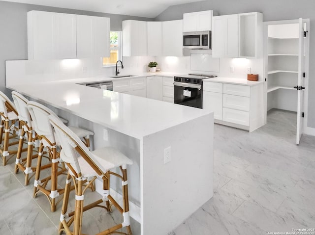 kitchen with marble finish floor, stainless steel microwave, electric range, a sink, and a kitchen bar