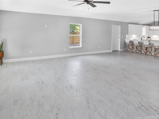 unfurnished living room with baseboards and ceiling fan with notable chandelier