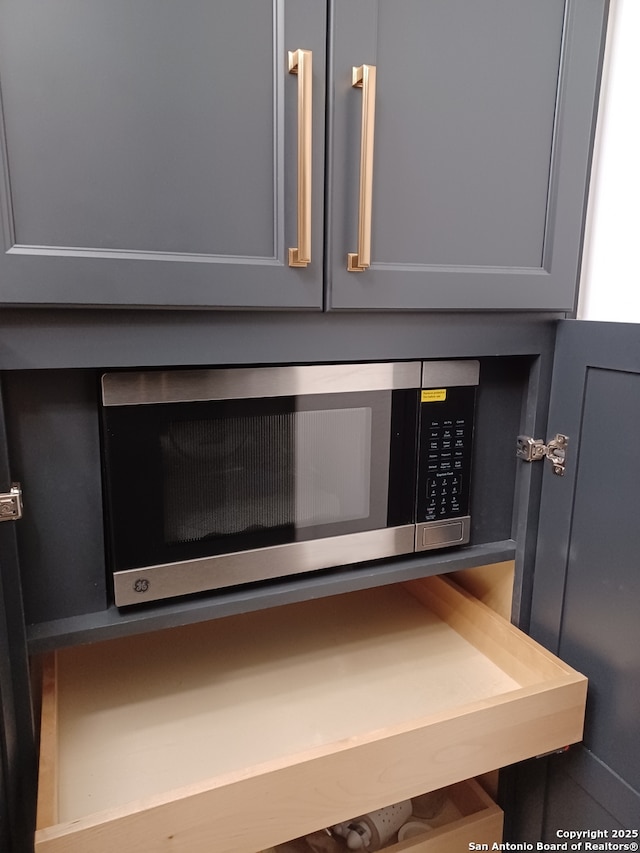 room details with gray cabinets, stainless steel microwave, and mail area