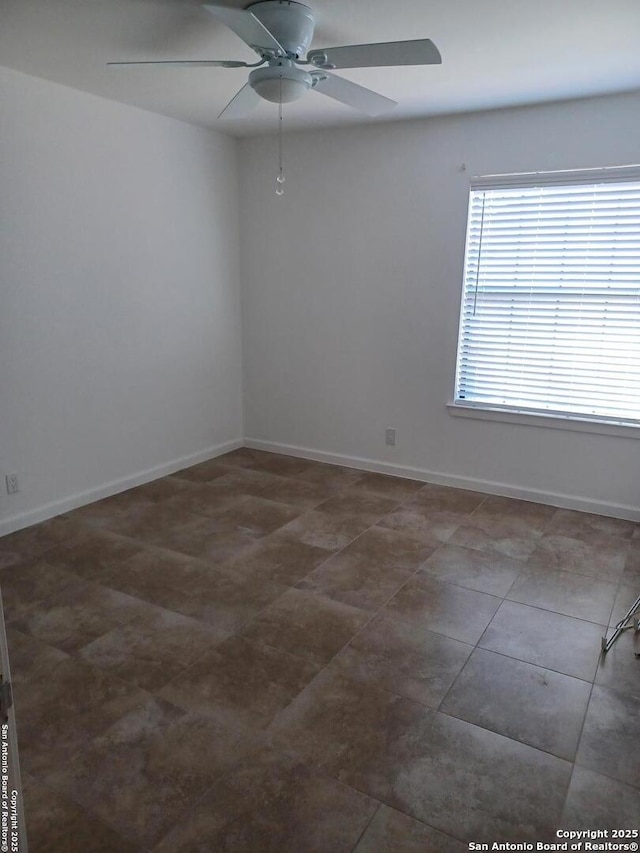 unfurnished room with ceiling fan and baseboards