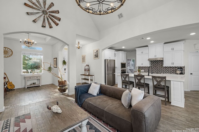 living room with visible vents, a notable chandelier, light wood-style flooring, and baseboards