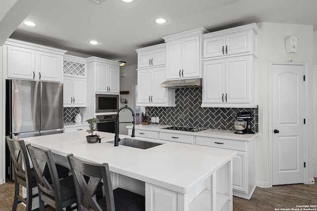 kitchen featuring light countertops, appliances with stainless steel finishes, a kitchen island with sink, a sink, and under cabinet range hood