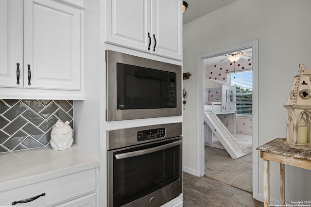 kitchen with wood finished floors, white cabinetry, stainless steel oven, backsplash, and built in microwave