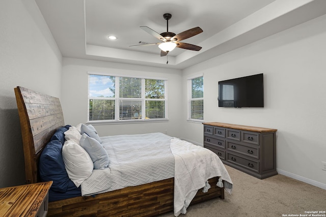 bedroom featuring ceiling fan, baseboards, a raised ceiling, and light colored carpet