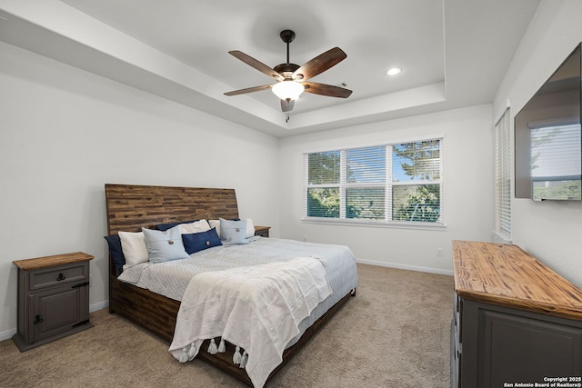 bedroom with ceiling fan, recessed lighting, light colored carpet, baseboards, and a tray ceiling