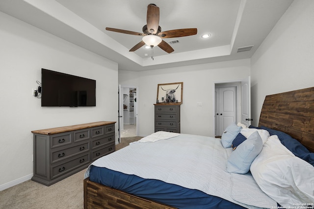 bedroom with light colored carpet, a tray ceiling, visible vents, and baseboards