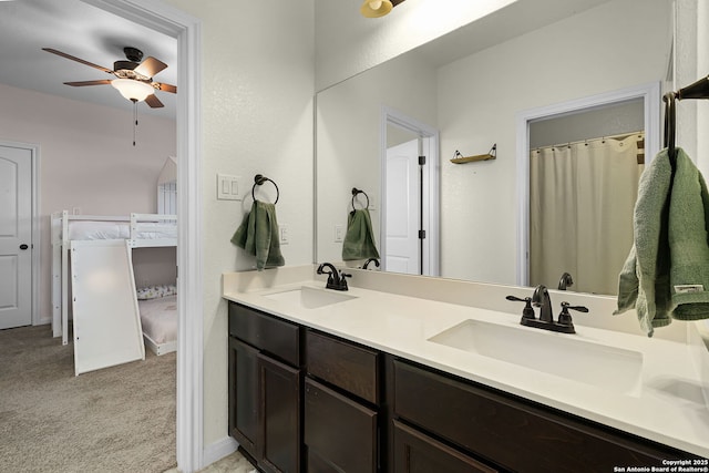 bathroom with double vanity, ceiling fan, baseboards, and a sink