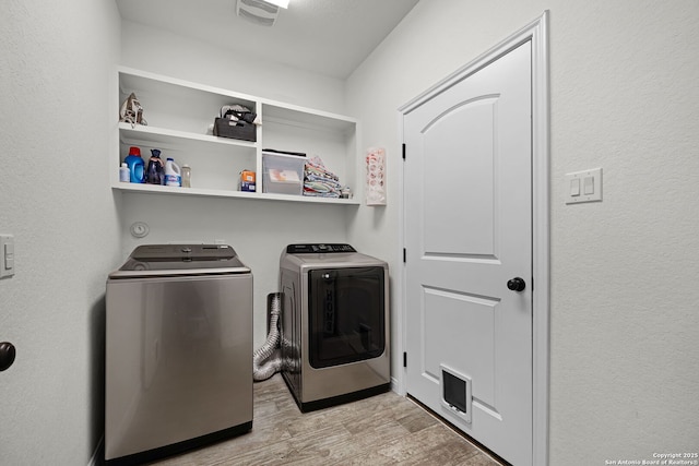 washroom featuring visible vents, laundry area, washing machine and clothes dryer, and light wood-style flooring