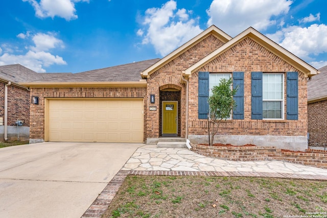 ranch-style home featuring concrete driveway, brick siding, an attached garage, and roof with shingles