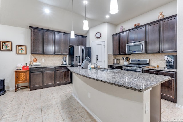 kitchen featuring light tile patterned floors, dark stone countertops, stainless steel appliances, dark brown cabinets, and a sink