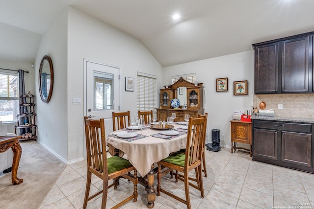 dining space featuring lofted ceiling, baseboards, and light tile patterned floors