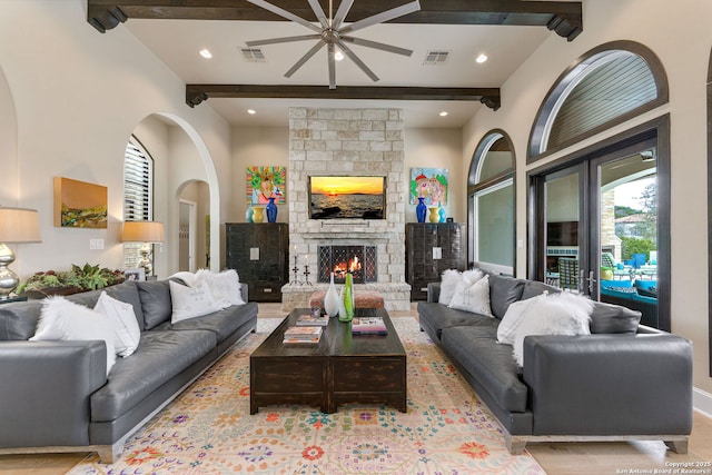 living area with a stone fireplace, beamed ceiling, visible vents, and recessed lighting