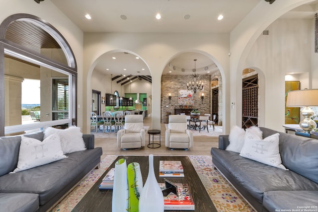 living area featuring a towering ceiling, a chandelier, wood finished floors, and recessed lighting