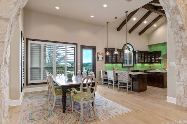 dining room featuring light wood finished floors, recessed lighting, high vaulted ceiling, beamed ceiling, and baseboards