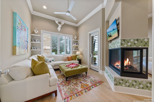 living room featuring ornamental molding, light wood-type flooring, a tile fireplace, and baseboards