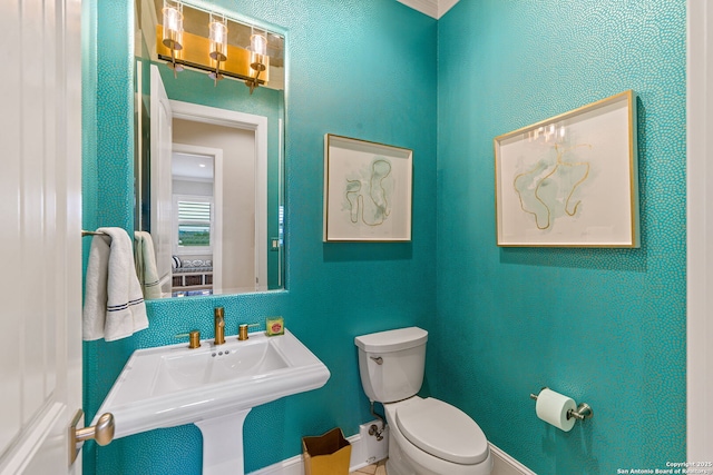 bathroom featuring toilet, baseboards, and a sink