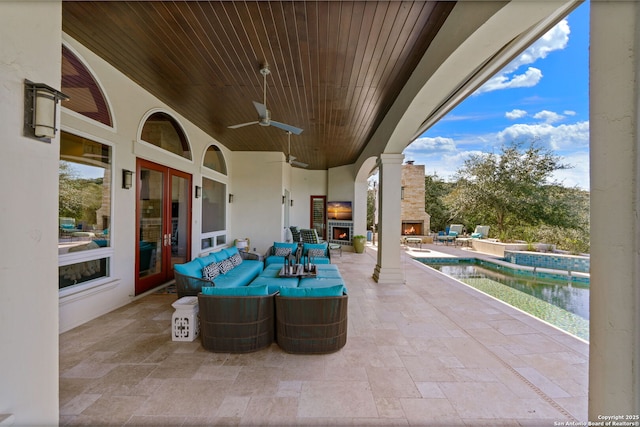 view of patio with french doors, an outdoor living space with a fireplace, and a ceiling fan