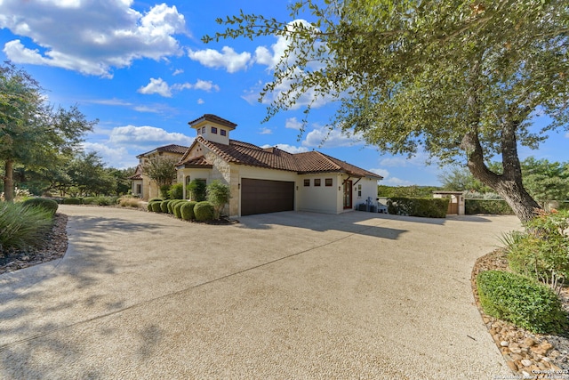 mediterranean / spanish-style home with a tile roof, driveway, an attached garage, and stucco siding