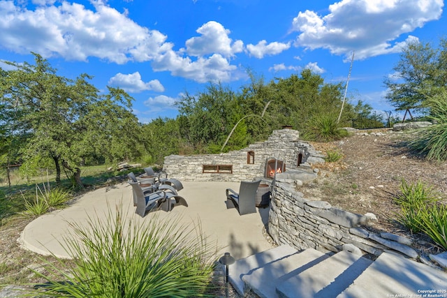 view of patio featuring an outdoor stone fireplace