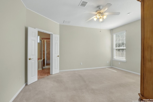 empty room with baseboards, visible vents, a ceiling fan, and light colored carpet