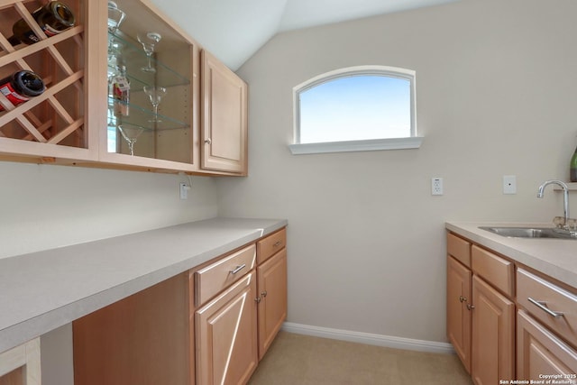 interior space with lofted ceiling, light colored carpet, a sink, light countertops, and glass insert cabinets