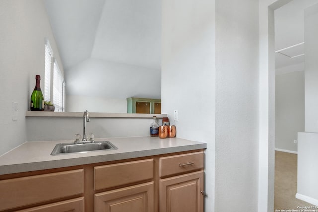 kitchen with lofted ceiling, light countertops, and a sink