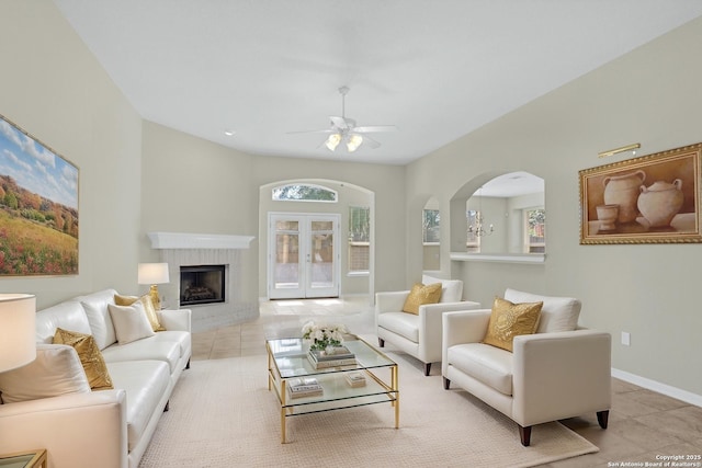 living area featuring arched walkways, light tile patterned floors, and plenty of natural light